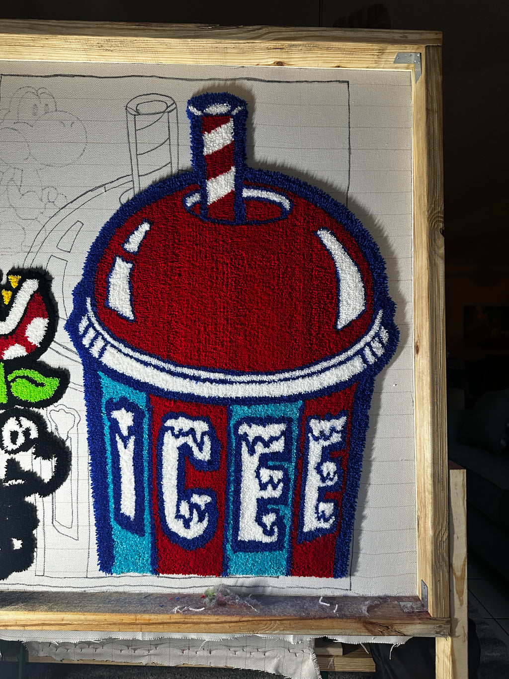 Colorful woven artwork with a prominent red and blue design on a wooden frame.